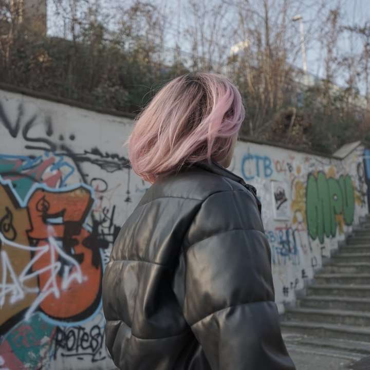 kvinna i svart jacka som står nära graffitiväggen Pussel online