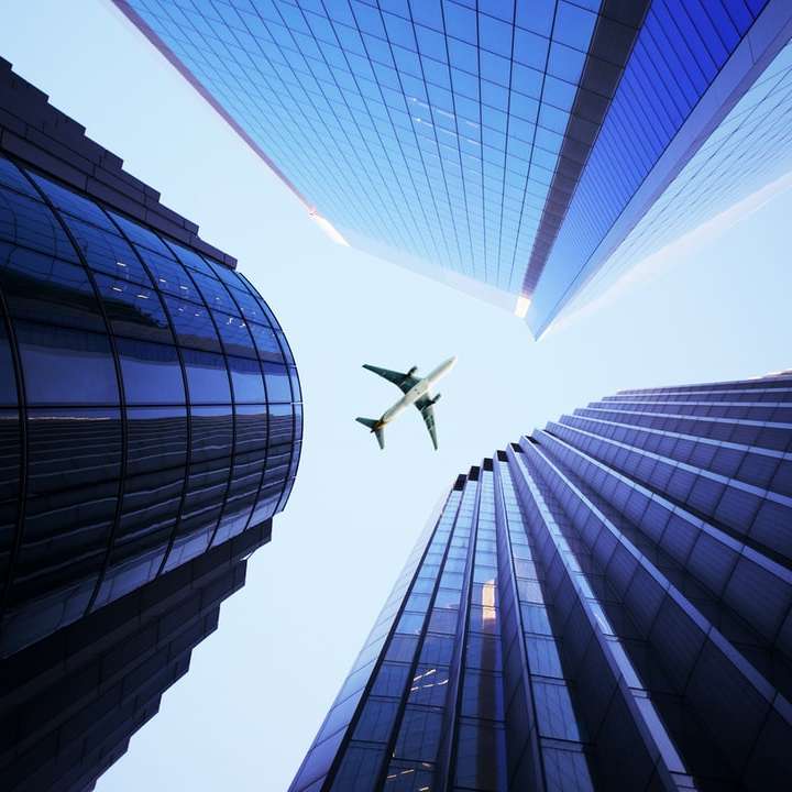 biały samolot lecący nad wieżowcem puzzle online