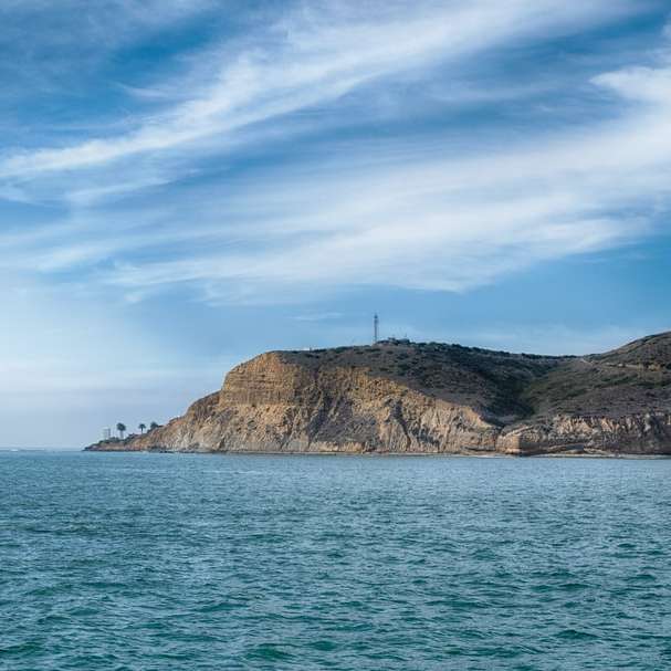 білий вітрильник на морі біля коричневої скелі розсувний пазл онлайн