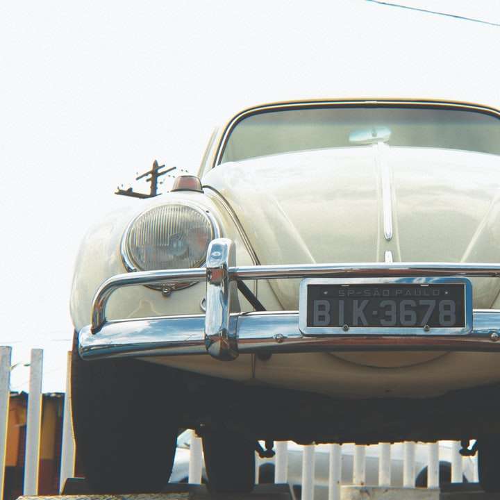 vit klassisk bil på en parkeringsplats under dagtid Pussel online