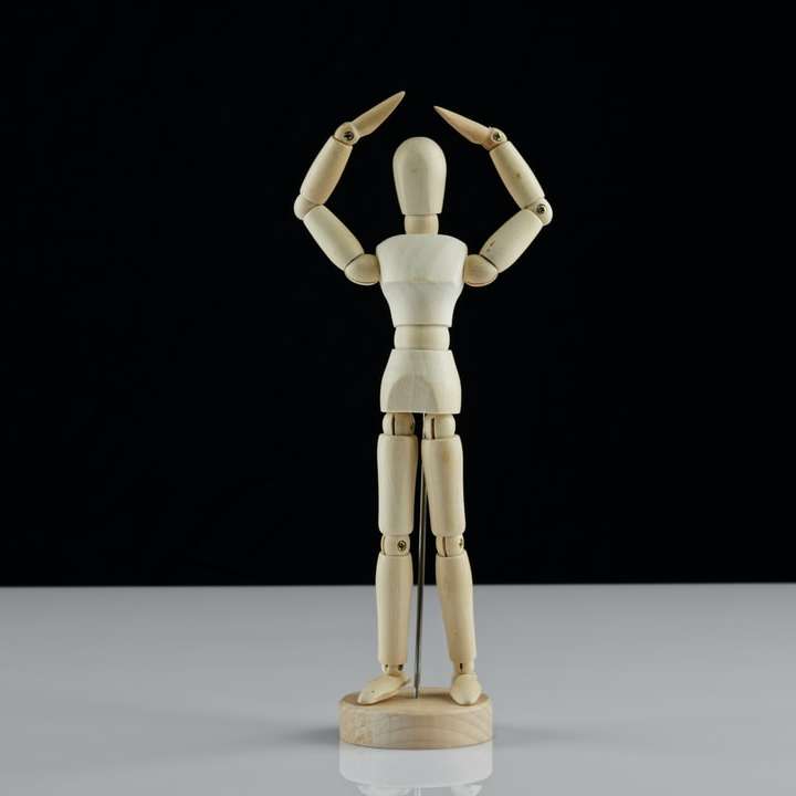 Figura humana de madera marrón sobre mesa blanca rompecabezas en línea