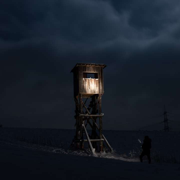 茶色の木造の塔の近くに立っている人のシルエット オンラインパズル