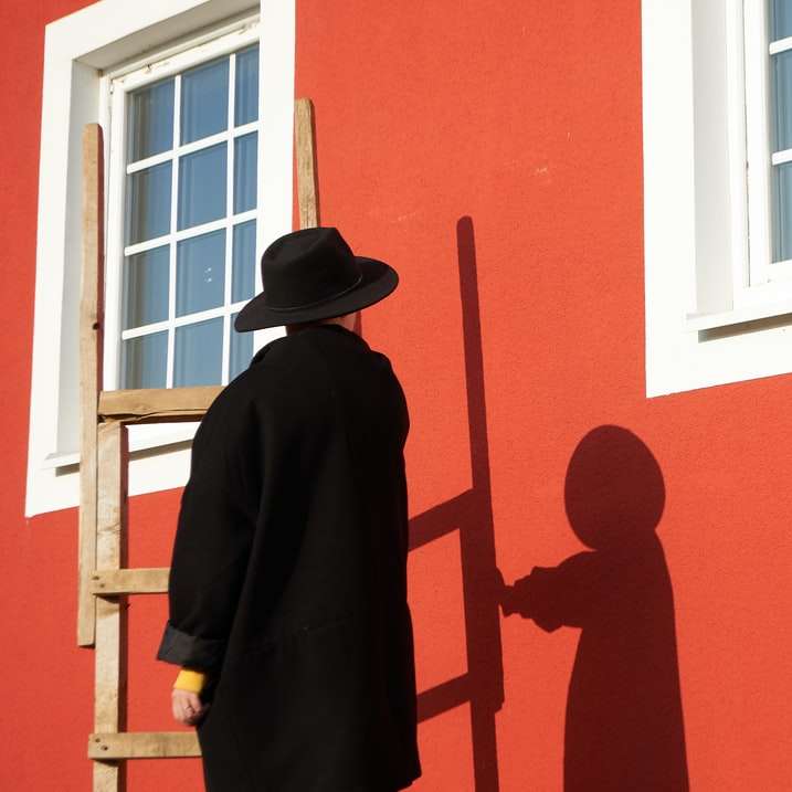 mężczyzna w czarnym kapeluszu stojący przed oknem puzzle przesuwne online