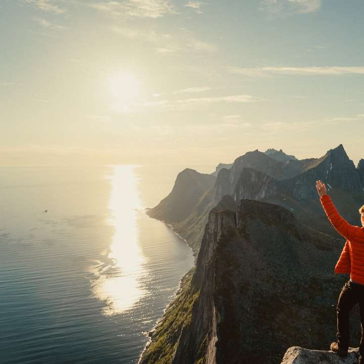 man in orange hoodie standing on rock formation sliding puzzle online