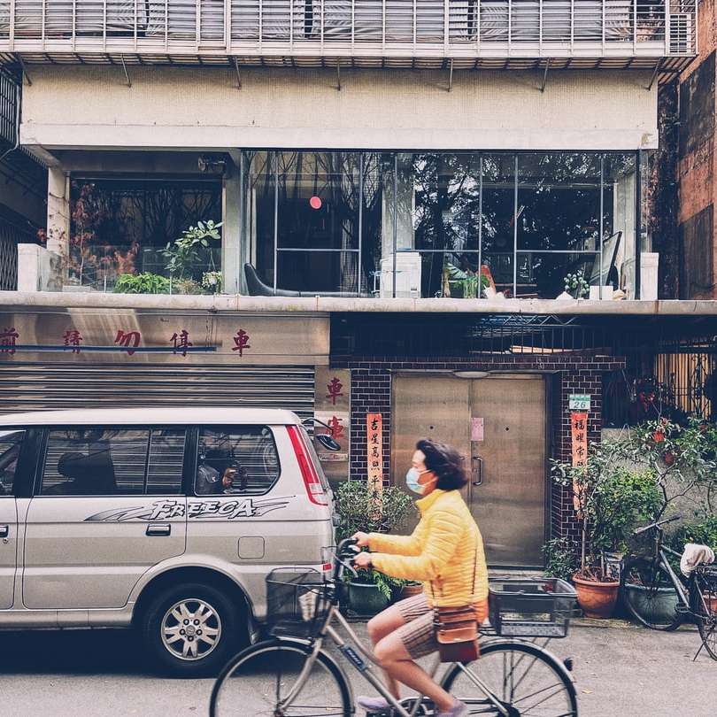 Mann im gelben Hemd, das Fahrrad nahe schwarzem Auto reitet Schiebepuzzle online