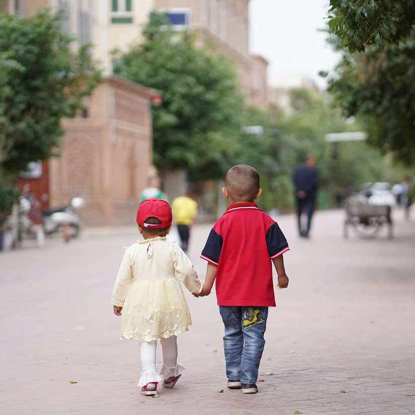 хлопчик у червоно-блакитній сорочці та сірі штани тримає дівчинку розсувний пазл онлайн