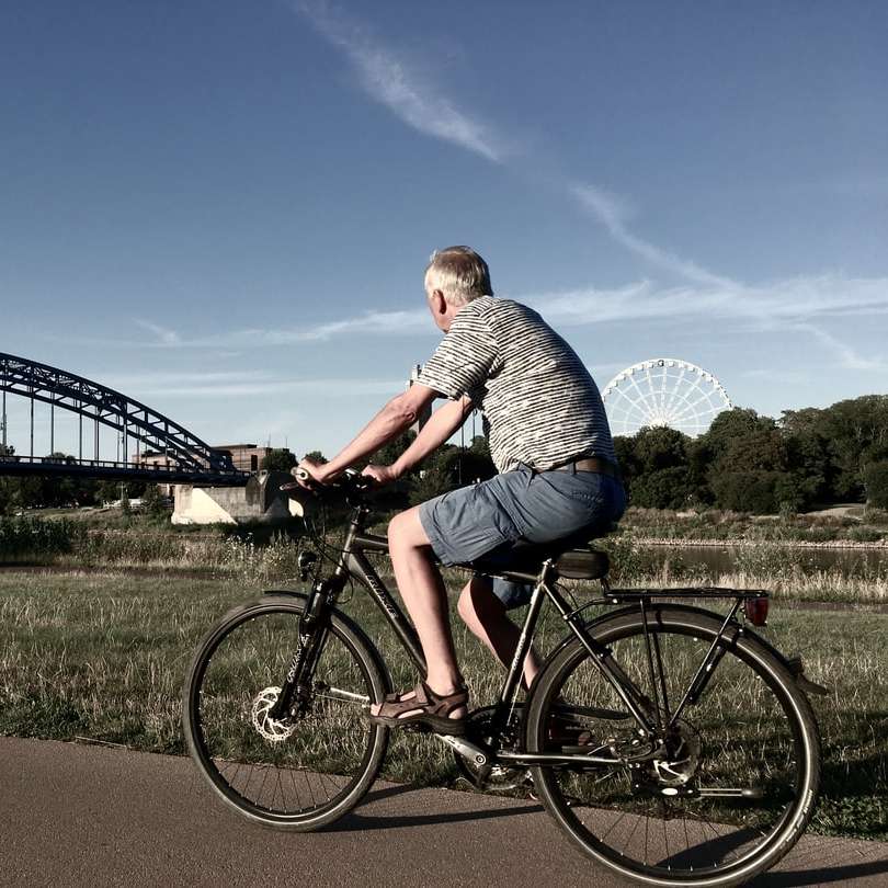 мъж в сива и бяла риза на райета, каращ черен велосипед плъзгащ се пъзел онлайн