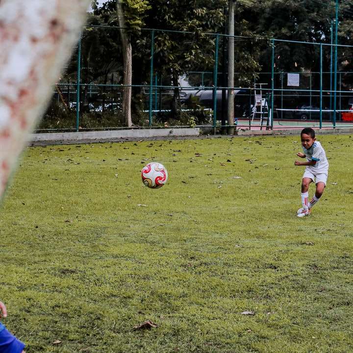 2 момчета, играещи футбол на поле със зелена трева през деня плъзгащ се пъзел онлайн