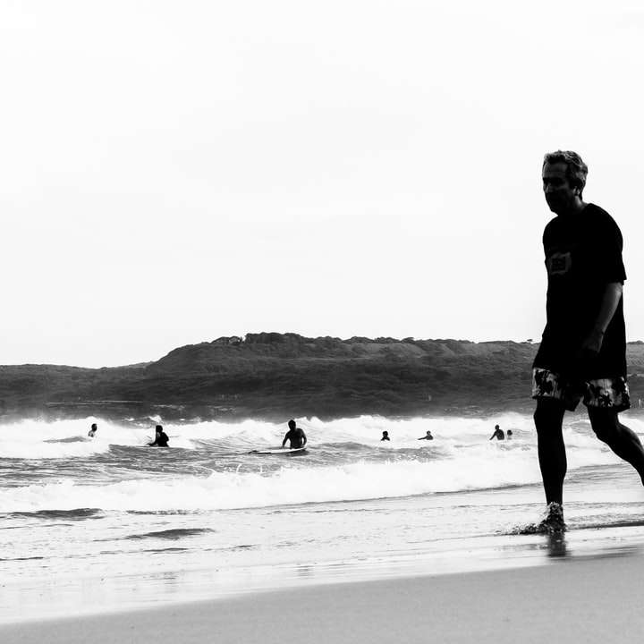 man in black jacket walking on beach sliding puzzle online