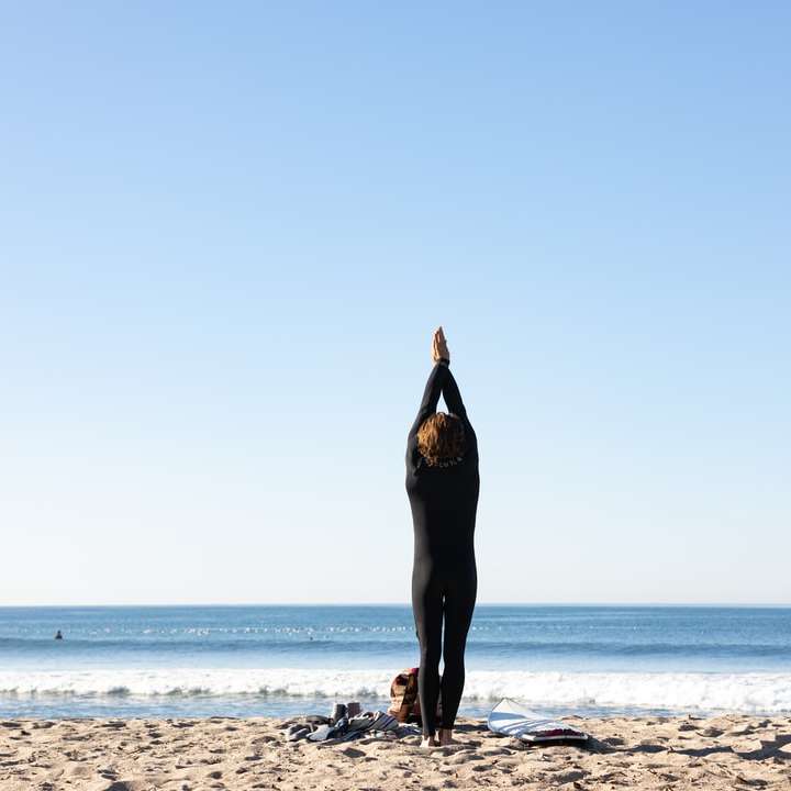 γυναίκα με μαύρο φόρεμα στέκεται στην παραλία κατά τη διάρκεια της ημέρας συρόμενο παζλ online
