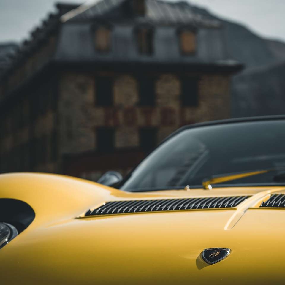 Porsche 911 galben parcat lângă clădirea din beton maro puzzle online
