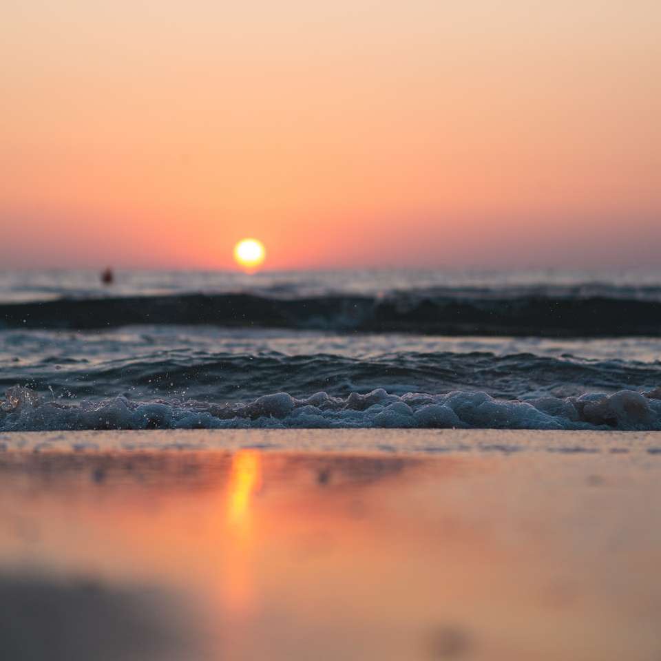 havsvågor som kraschar på stranden under solnedgången glidande pussel online