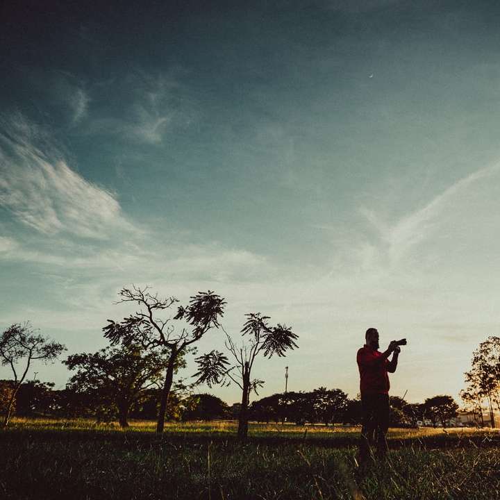 homem de jaqueta preta em pé no campo de grama verde puzzle online