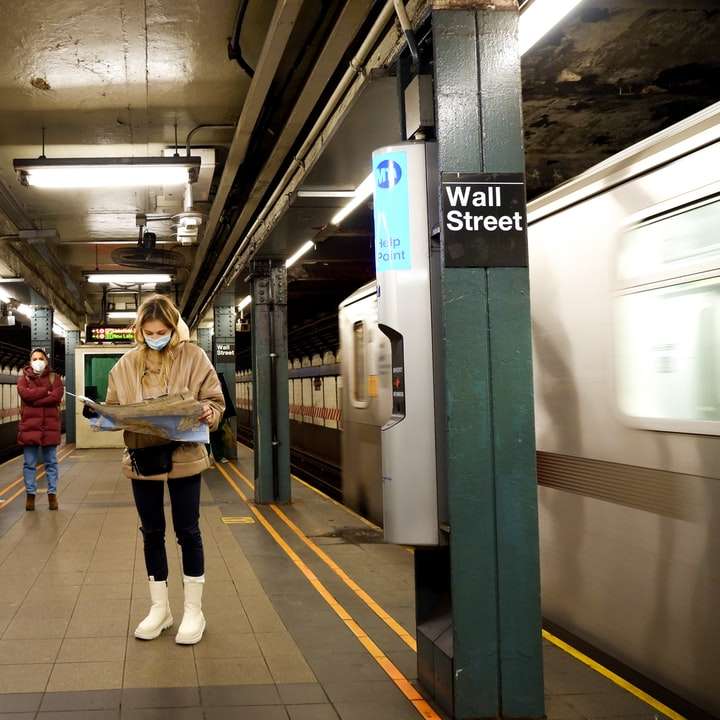 Frau im braunen Mantel stehend auf Bahnhof Schiebepuzzle online