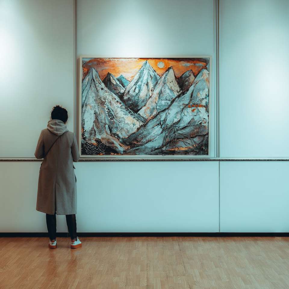 femme en manteau gris debout près de la peinture puzzle coulissant en ligne