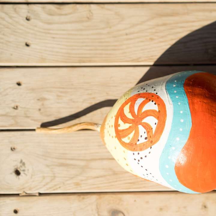 Botella de plástico naranja y blanco sobre mesa de madera marrón rompecabezas en línea