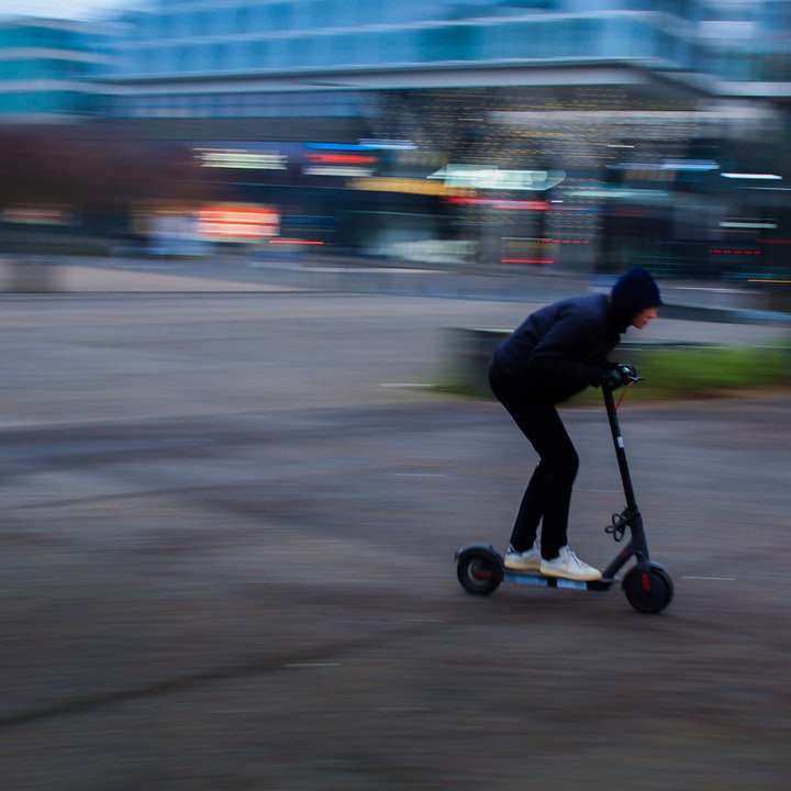 мъж в черно яке, каране на черен скутер на пътя плъзгащ се пъзел онлайн