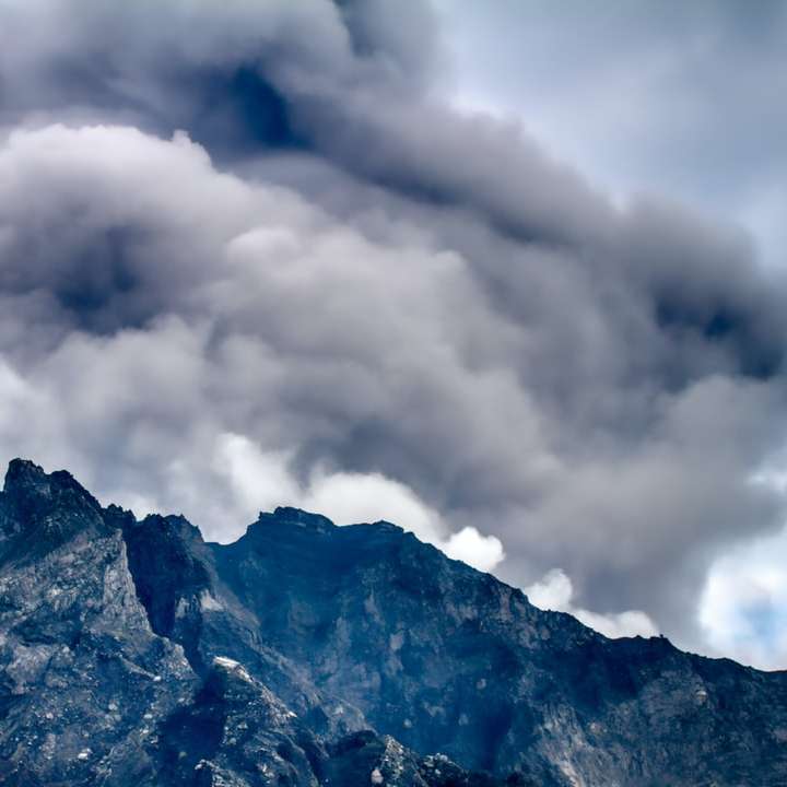 άσπρα σύννεφα πάνω από καφέ και μαύρο βουνό online παζλ