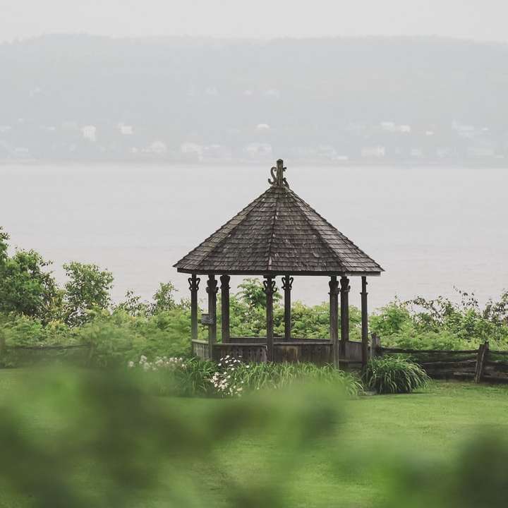 schwarzer hölzerner Pavillon auf grünem Grasfeld nahe dem Gewässer Schiebepuzzle online