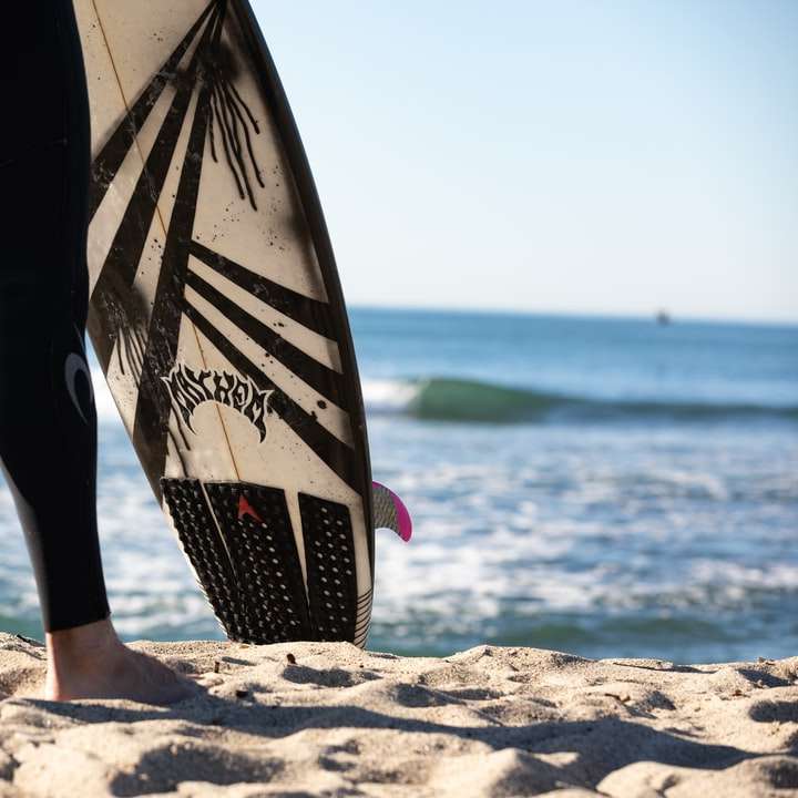 person holding black and white surfboard sliding puzzle online