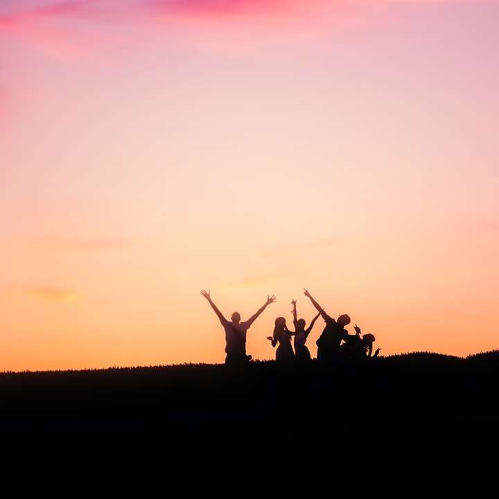 silhouet van mensen bovenop berg tijdens zonsondergang schuifpuzzel online