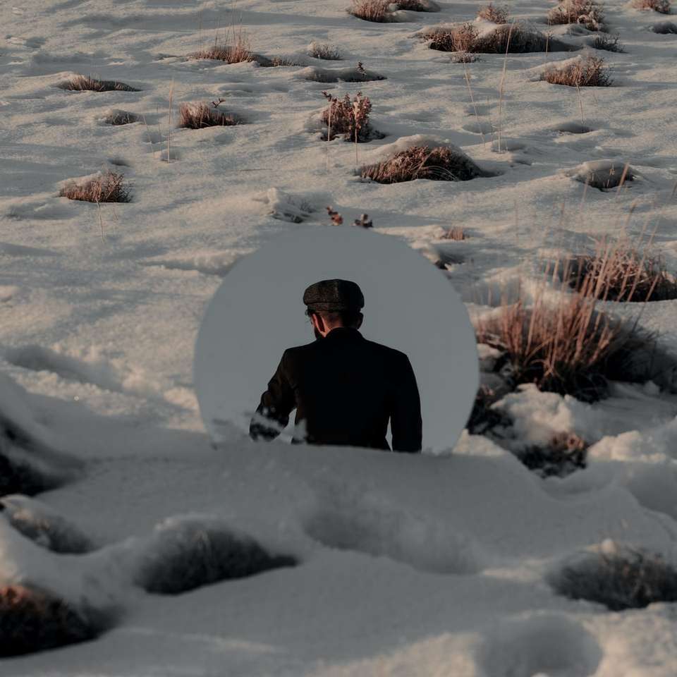 Человек в черном пальто сидит на заснеженной земле раздвижная головоломка онлайн