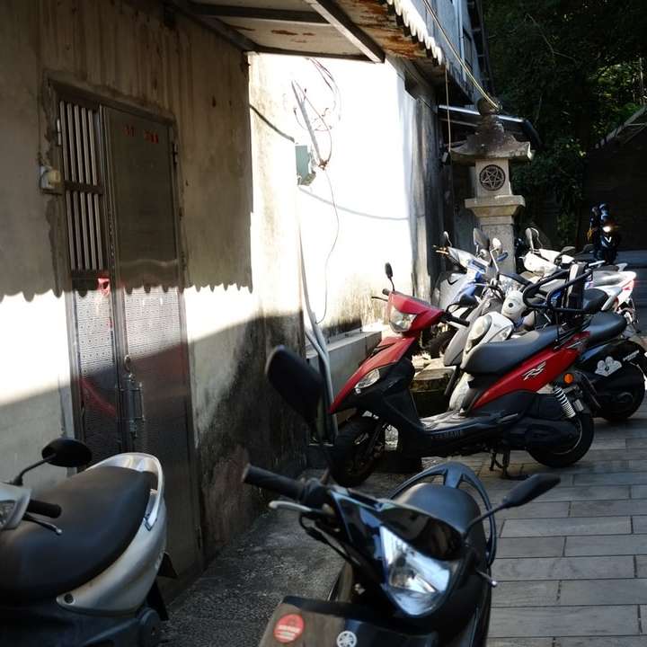 白いコンクリートの建物の横に駐車された黒と赤のオートバイ スライディングパズル・オンライン