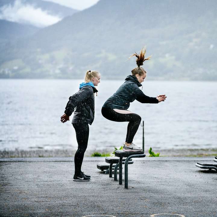 woman in pink jacket and black pants jumping on black bench online puzzle