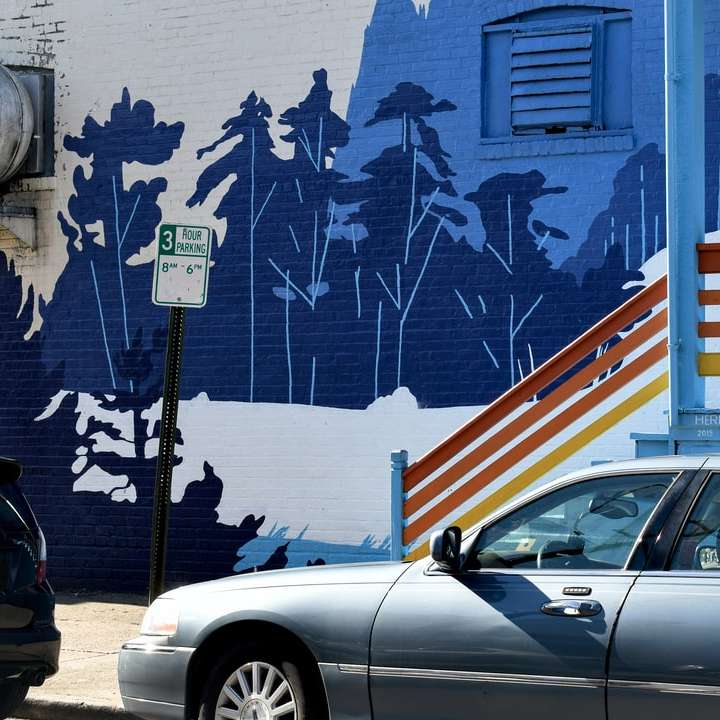 青と白の塗られた壁の横に駐車された白いクーペ オンラインパズル