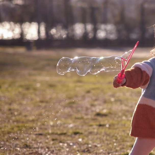 дівчина в біло-червоній сукні грає бульбашки в денний час онлайн пазл