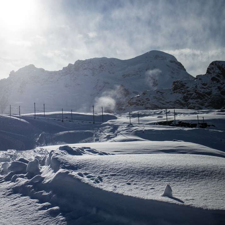 campo coberto de neve e montanha durante o dia puzzle deslizante online
