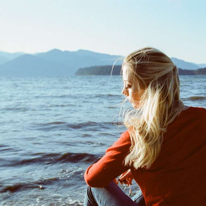 donna in camicia a maniche lunghe marrone rossiccio in piedi sulla riva del mare puzzle scorrevole online