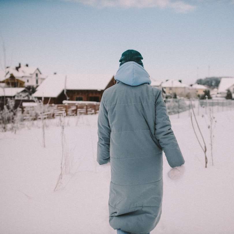 osoba w szarym płaszczu zimowym stojąca na ziemi pokrytej śniegiem puzzle online