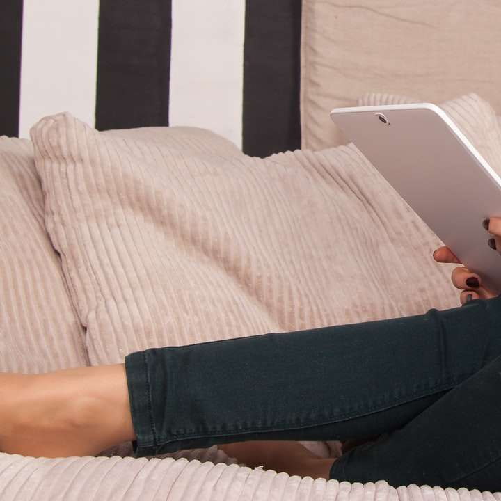 person in white shirt and black pants holding white ipad sliding puzzle online