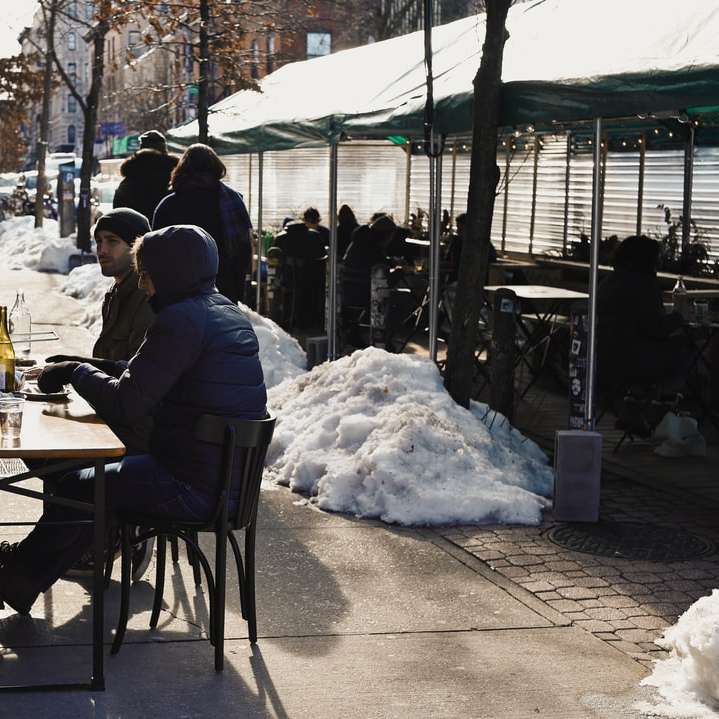 ludzie siedzący na krześle przed stołem pokrytym śniegiem puzzle przesuwne online