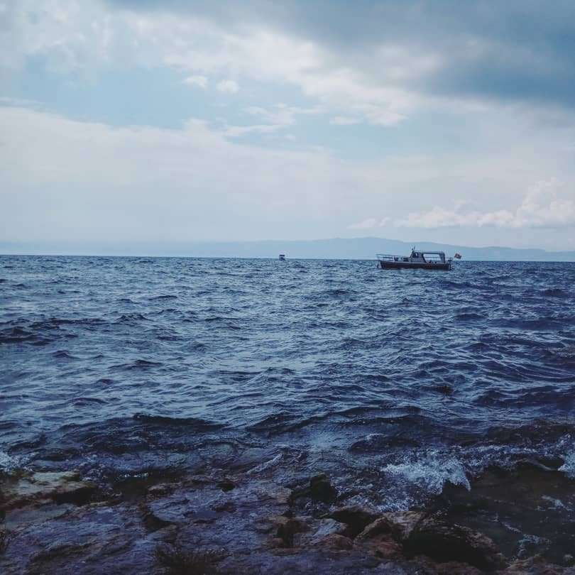 λευκή βάρκα στη θάλασσα κάτω από άσπρα σύννεφα κατά τη διάρκεια της ημέρας συρόμενο παζλ online
