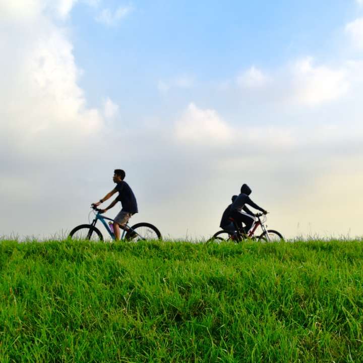 uomo in camicia nera, andare in bicicletta sul campo di erba verde puzzle scorrevole online