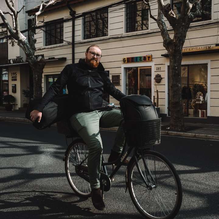 мъж в черно яке, каране на черен велосипед плъзгащ се пъзел онлайн