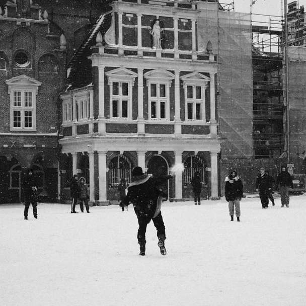 Personnes marchant sur un champ couvert de neige près du bâtiment puzzle coulissant en ligne