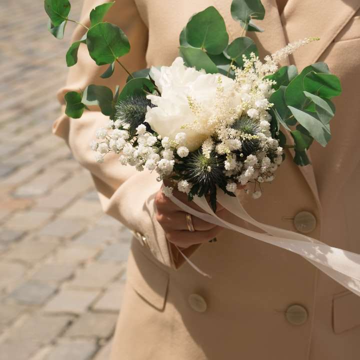 Mujer en chaqueta beige con ramo de flores blancas puzzle deslizante online