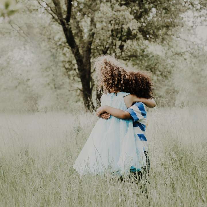 flicka i vit och blå klänning som står på fältet för grönt gräs glidande pussel online