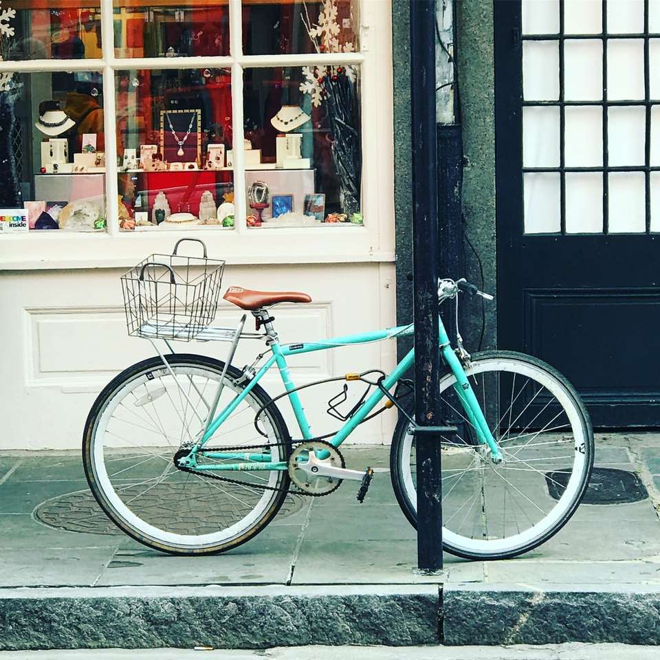 Vélo de ville sarcelle garé à côté du magasin puzzle coulissant en ligne