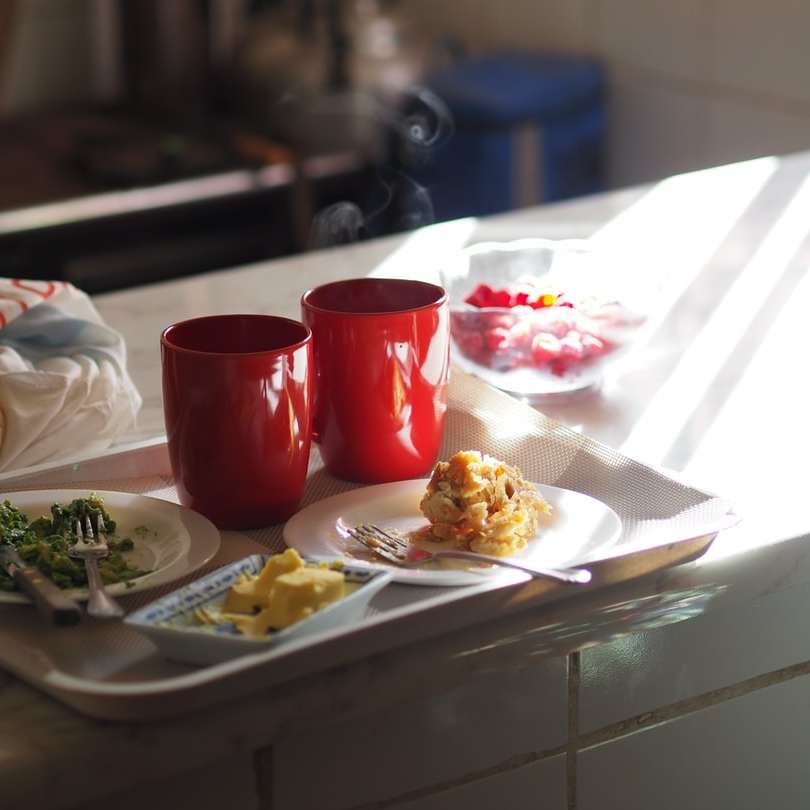 Taza de cerámica roja junto a la placa de cerámica blanca en la mesa puzzle deslizante online