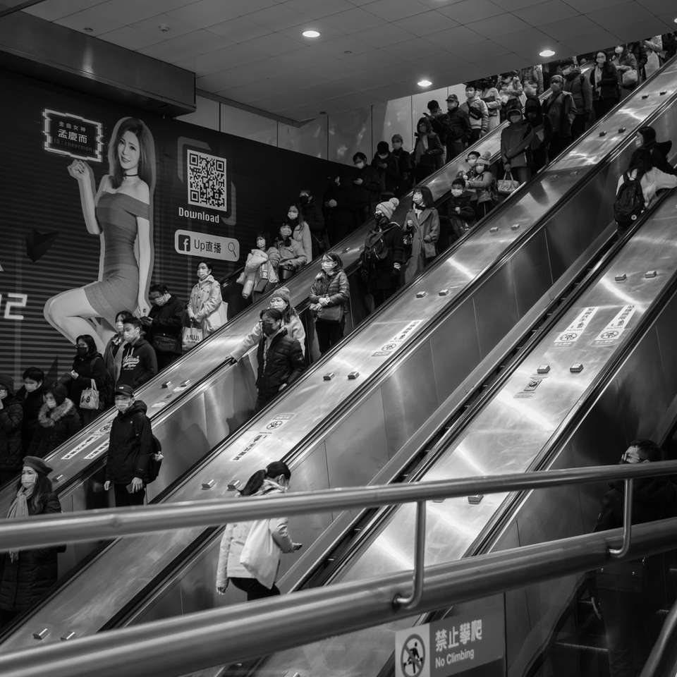 Foto en escala de grises de personas en una escalera mecánica. puzzle deslizante online