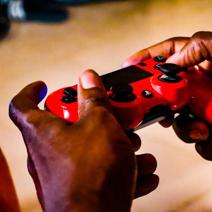 άτομο που κρατά τον κόκκινο και μαύρο ελεγκτή παιχνιδιών συρόμενο παζλ online