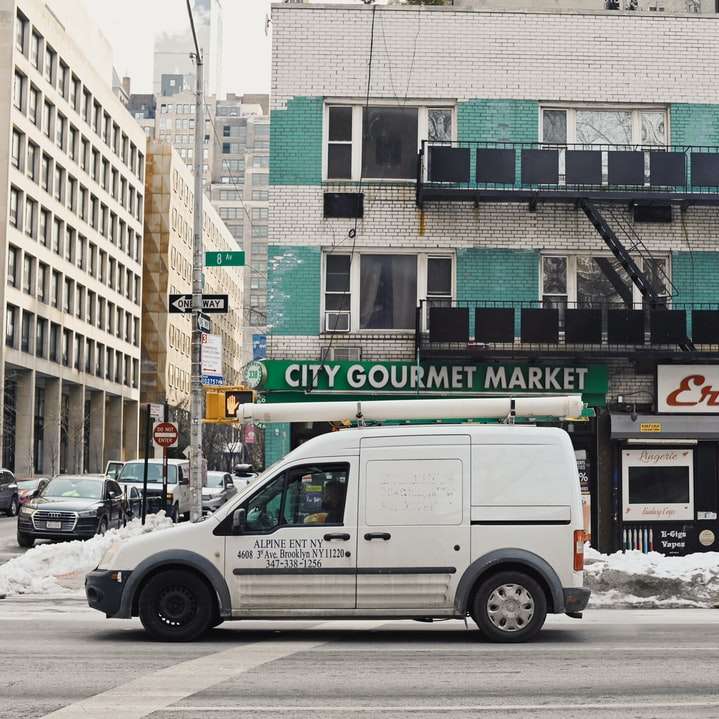 vit skåpbil parkerad framför byggnaden under dagtid Pussel online