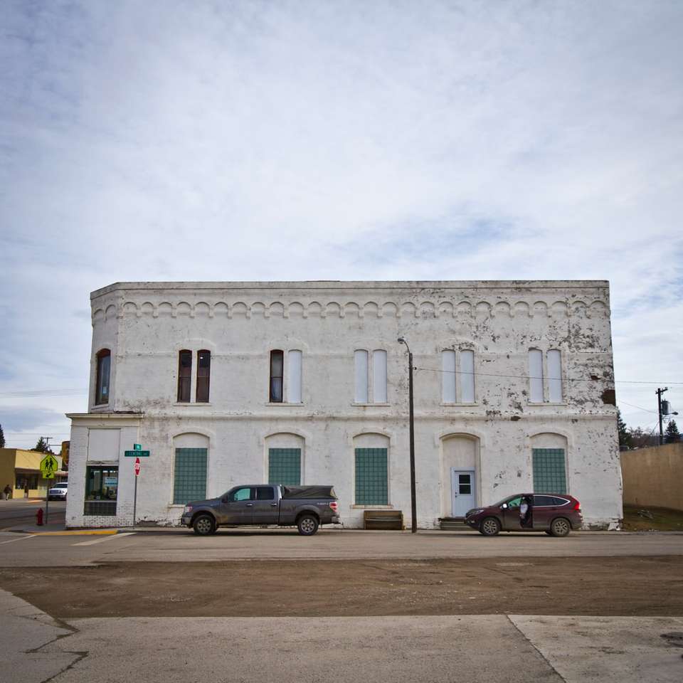 voitures garées devant un bâtiment en béton blanc puzzle coulissant en ligne