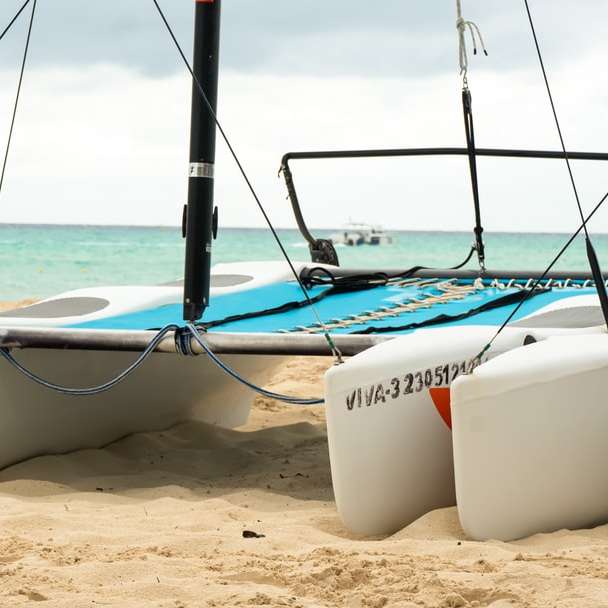 weißes und schwarzes Segelboot auf weißem Sand während des Tages Schiebepuzzle online
