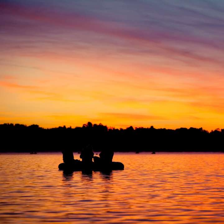 silhouette of 2 person on body of water during sunset online puzzle