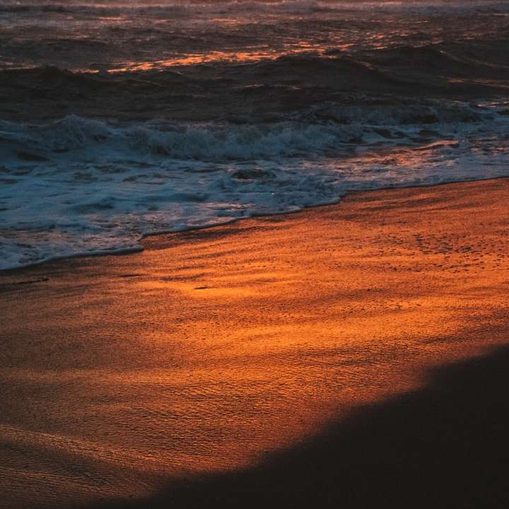 Ozeanwellen, die während des Sonnenuntergangs am Ufer abstürzen Online-Puzzle